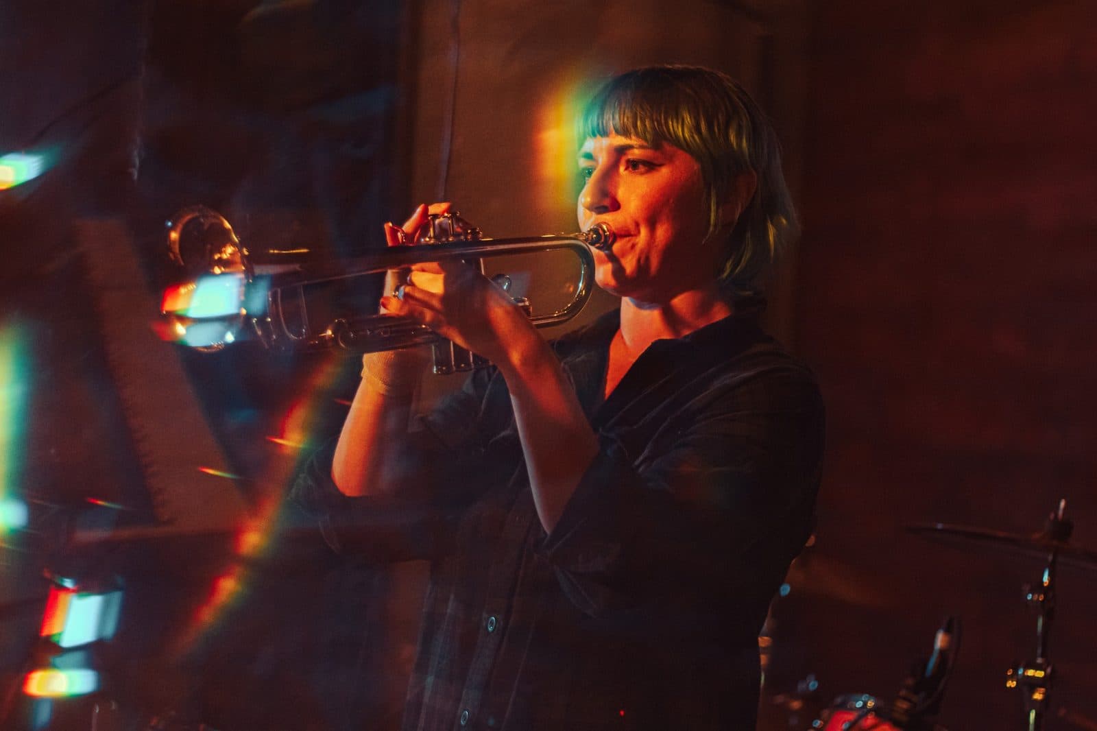Trumpet player performing on stage under warm red and orange light
