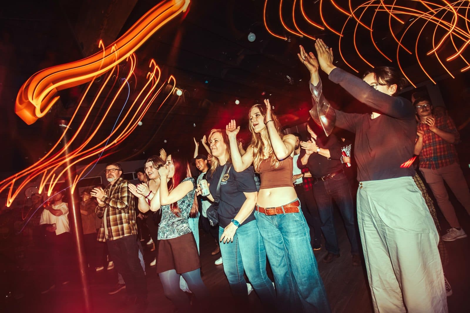 Audience clapping under red stage light trails at a Champions of Hope show