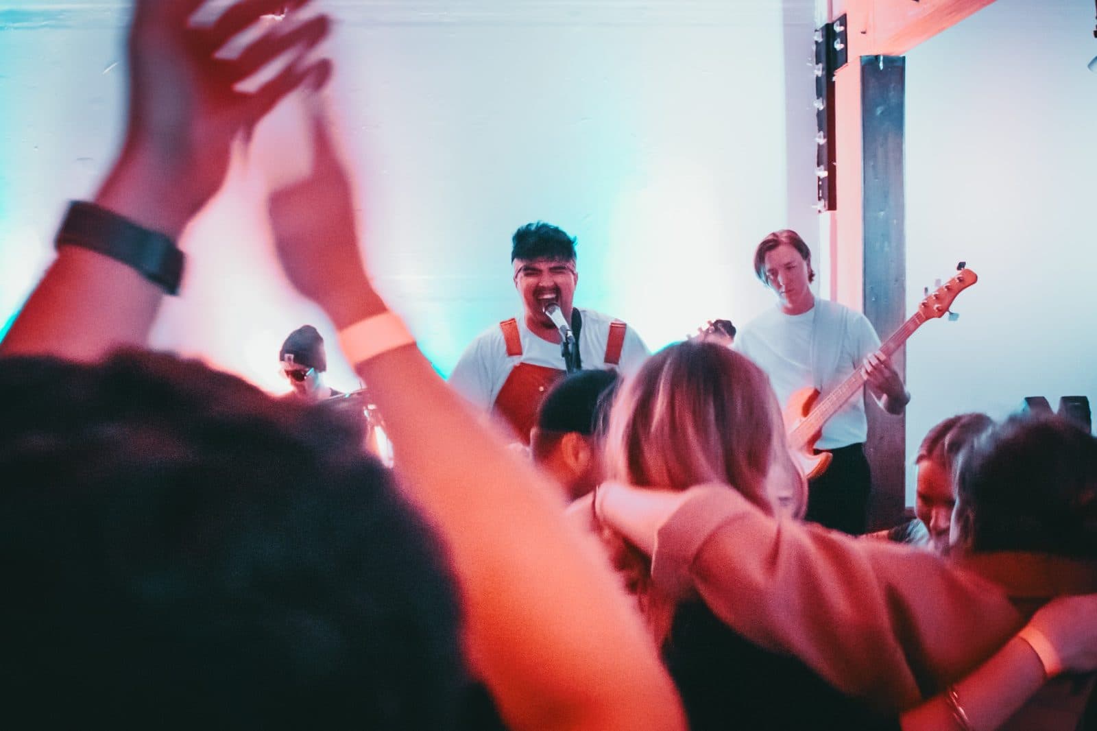 Band performing to a crowd with raised hands at a Champions of Hope show