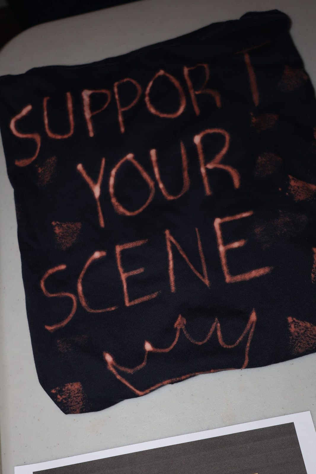 Support your scene shirt displayed on a table at a Champions of Hope event