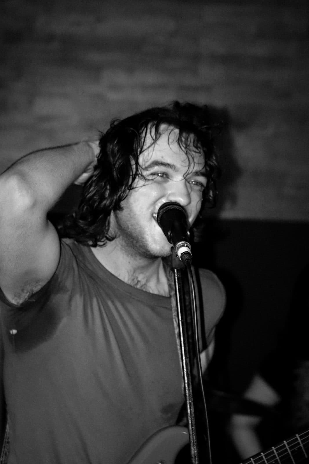 Black and white close-up of a vocalist singing into a microphone